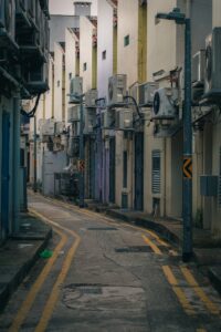 View of a tight urban alleyway lined with air conditioning units on older buildings.